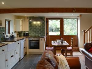 a kitchen and living room with a couch and a table at Bryn Dedwydd Cottage in Llanferres