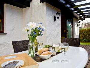 una mesa con copas de vino y flores. en Clematis, en Saint Wenn