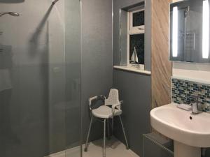 a bathroom with a shower and a sink and a stool at Driftwood in Mainsriddle