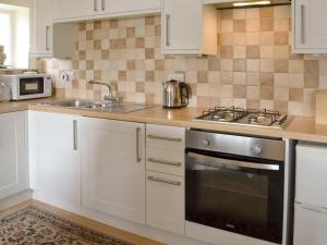 a kitchen with white cabinets and a sink and a stove at Temple House West in Drumnadrochit