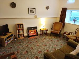 a living room with a fireplace and a tv at Knock School Cottage in Monreith