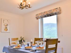 a dining room with a table with food and a window at Carron View in Strathcarron