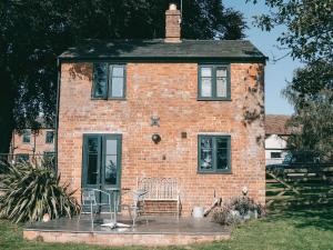 a brick house with chairs and a table in front of it at Southfield Cottage in Braunston