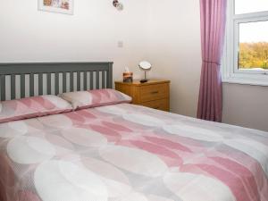 um quarto com uma cama rosa e branca e uma janela em Y Ddol em Caeathro