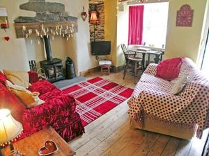 a living room with a red couch and a fireplace at Rustic Cottage in Bowness-on-Windermere