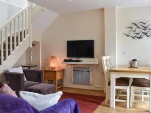 a living room with a dining room table and a tv at Oak Tree Cottage in Otterburn