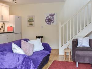 a living room with a purple couch and a chair at Oak Tree Cottage in Otterburn