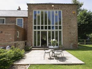 a patio with a table and chairs in front of a building at Curlew Barn in Sutton Bridge