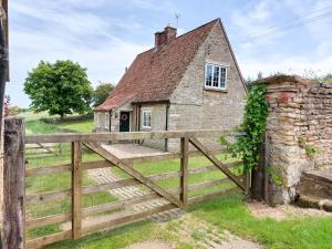 an old house with a wooden fence and a gate at Moorhouse Farm Cottage in Hovingham
