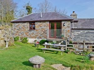 a stone house with a picnic table in the yard at Tripp Cottage in Saint Neot