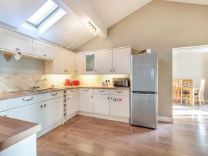 a kitchen with white cabinets and a stainless steel refrigerator at Barn Owl Cottage in Wisbech