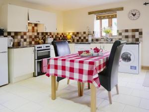 a kitchen with a table with a red and white checkered table cloth at Hawthorn in Hartland