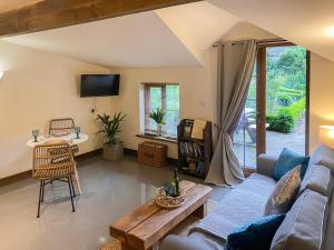 een woonkamer met een bank en een tafel bij Bluebell Cottage - 27635 in Darenth