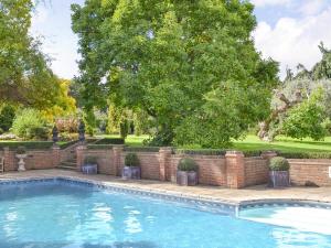 una piscina con una pared de ladrillo y un árbol en Bluebell Cottage - 27635 en Darenth