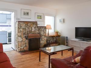 a living room with a couch and a stone fireplace at Seaspray in Camber