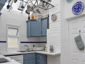 a kitchen with blue cabinets and a sink at Seaspray in Camber