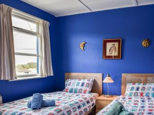 a blue bedroom with two beds and a window at Seaspray in Camber