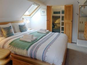 a bedroom with a large bed with towels on it at Heale Cottage - 28087 in Littleham
