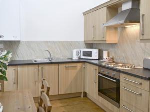 a kitchen with wooden cabinets and a microwave and a table at The Bridles -26718 in North Willingham