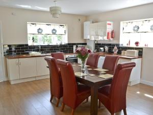 - une cuisine avec une table en bois, des chaises et une table dans l'établissement Abbey Cottage, à Longhirst