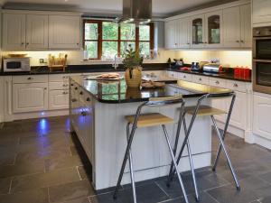 a kitchen with white cabinets and a island with two bar stools at Church View in Crackington Haven