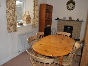 einen Holztisch und Stühle in einem Zimmer mit Kamin in der Unterkunft Shore Cottage in Silverdale