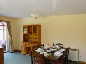 una sala da pranzo con tavolo, sedie e bottiglie di vino di Cotterton Beag a Nethy Bridge