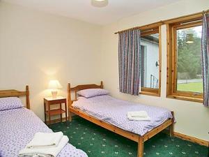 two twin beds in a room with a window at Cotterton Beag in Nethy Bridge