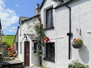 Una casa blanca con flores a un lado. en Hidden Cottage en Spark Bridge