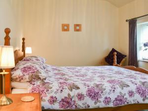 1 dormitorio con 1 cama y 1 mesa con lámpara en Llofft Yr Yd - 16984, en Brynsiencyn