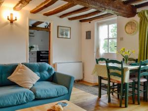 a living room with a blue couch and a table at Three Ash Cottage in Bungay