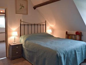 a bedroom with a bed with a blue comforter at Three Ash Cottage in Bungay