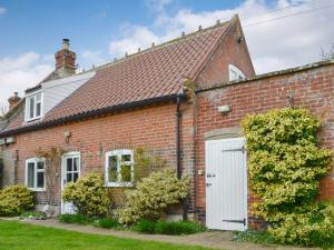 a red brick house with a white door at Three Ash Cottage in Bungay