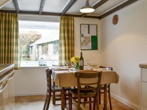 cocina con mesa con sillas y ventana en Blairhosh Cottage, en Balloch