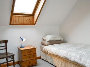 a bedroom with a bed and a chair and a window at Blairhosh Cottage in Balloch