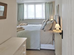 Schlafzimmer mit einem weißen Bett und einem Fenster in der Unterkunft Dove Cottage in Halesworth