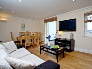 a living room with a white couch and a tv at The Cottage - Goodrington Lodge in Paignton
