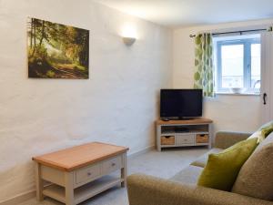 a living room with a couch and a tv at Ash in Scorrier