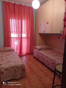 een kamer met 2 bedden en een raam met roze gordijnen bij bandiera blu in Marina di Gioiosa Ionica