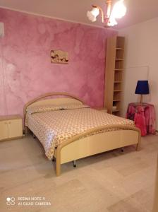 um quarto com uma cama e uma parede rosa em bandiera blu em Marina di Gioiosa Ionica