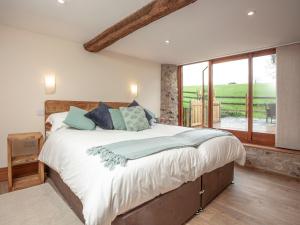 a bedroom with a large bed and a large window at Gittishayne Farm Barn in Colyton