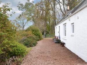 a white house with a gravel path next to it at Culcharry Cottage in Cawdor