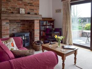 a living room with a couch and a fireplace at Pond Cottage in Peasmarsh