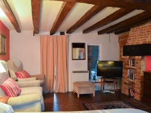 a living room with a couch and a television at Tudor Cottage Studio in Romsey