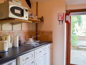 cocina con fregadero y microondas en Tudor Cottage Studio en Romsey