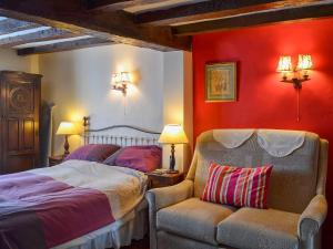 a bedroom with red walls and a bed and a chair at Tudor Cottage Studio in Romsey