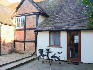 a patio with two chairs and a table in front of a house at Tudor Cottage Studio in Romsey