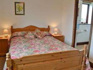 PeasmarshにあるPond Cottageのベッド1台(ナイトスタンド2台、ランプ2つ付)
