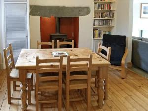 mesa de comedor de madera con sillas y estufa de leña en Glenmore Cottage, en Ambleside