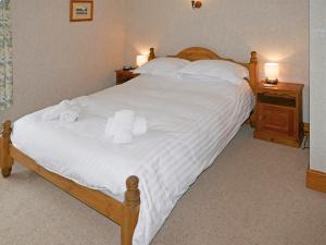1 dormitorio con 1 cama con sábanas blancas y toallas en Glenmore Cottage, en Ambleside
